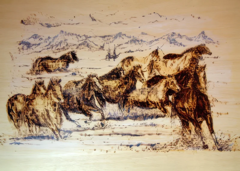 A group of horses with a distant mountain landscape on a pale wooden surface.